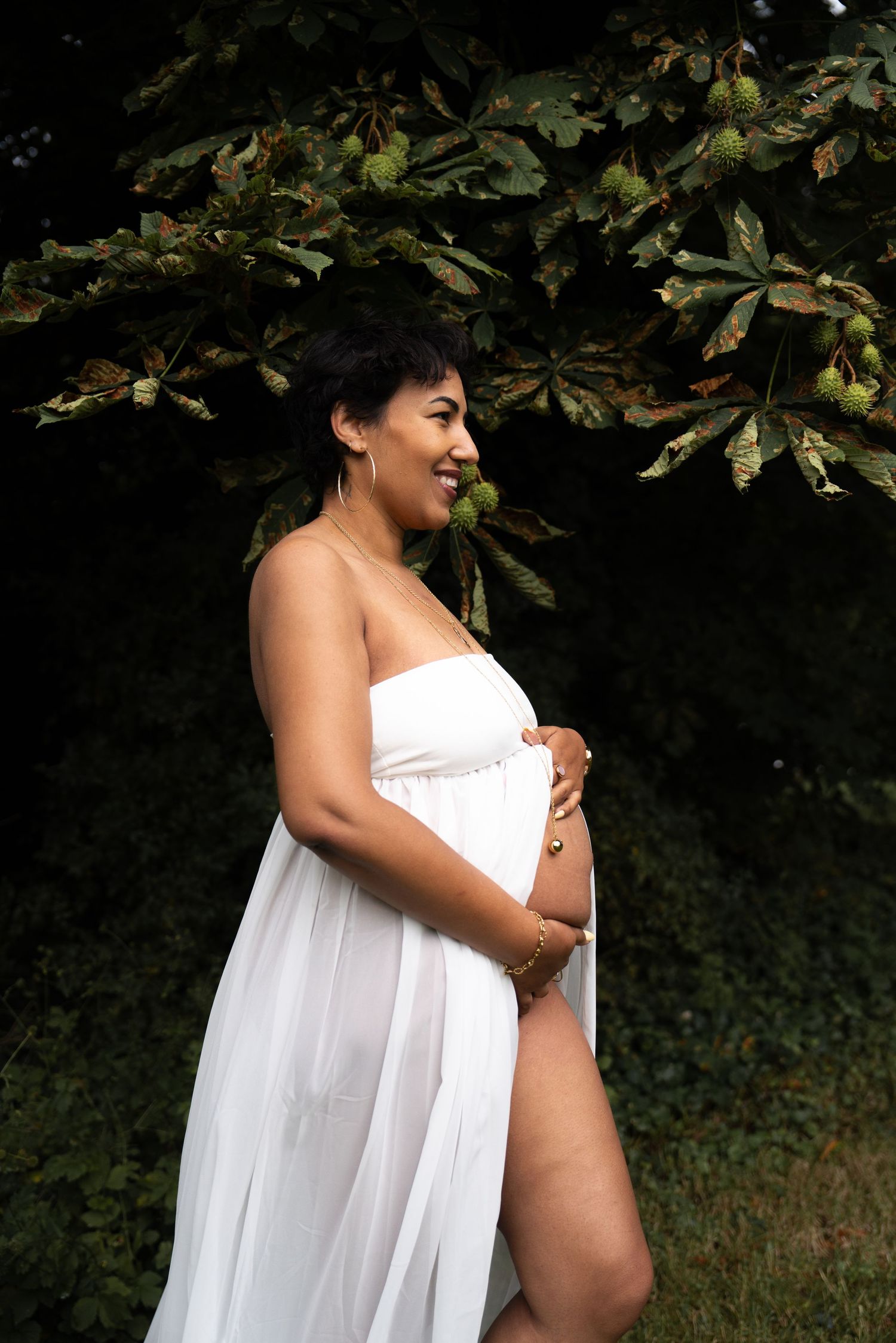 Femme enceinte en robe blanche dans un jardin, shooting grossesse en Guyane