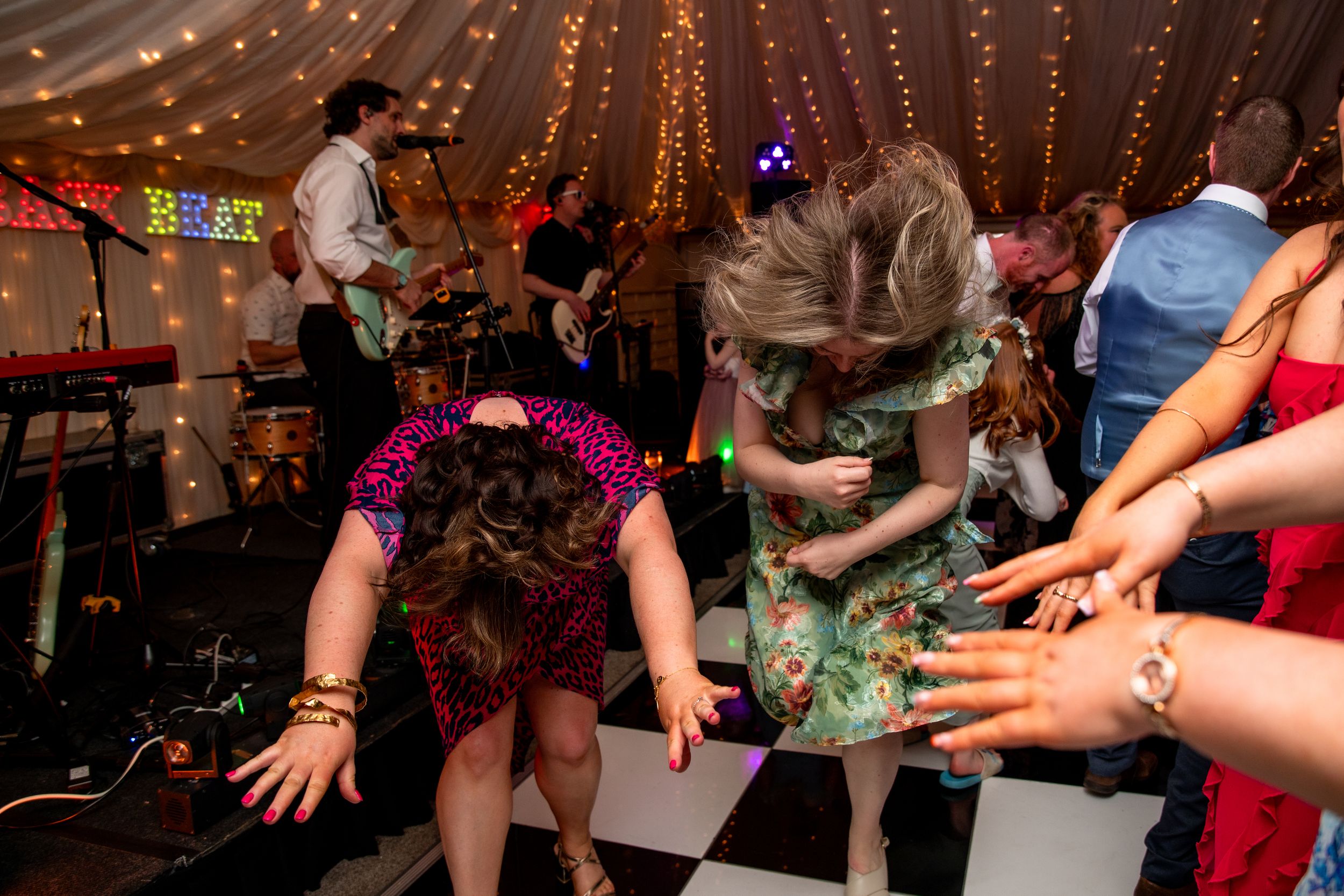 People dancing and having fun on a dance floor under string lights at a party celebration event.