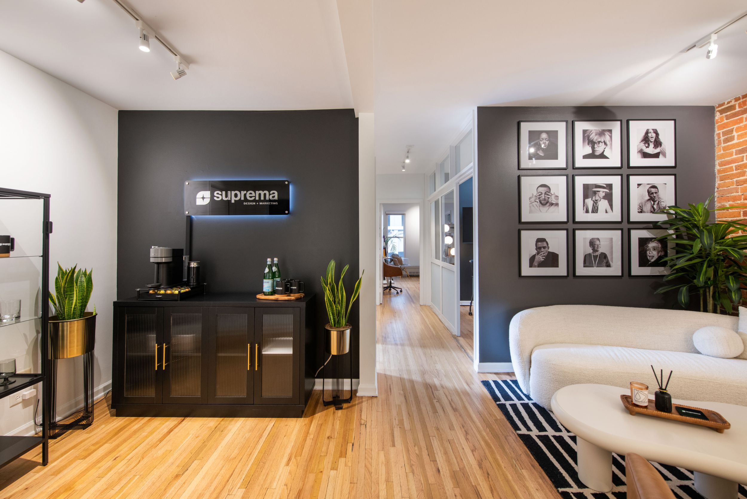 Contemporary office space with reception desk, gallery wall, and white seating area on striped rug.