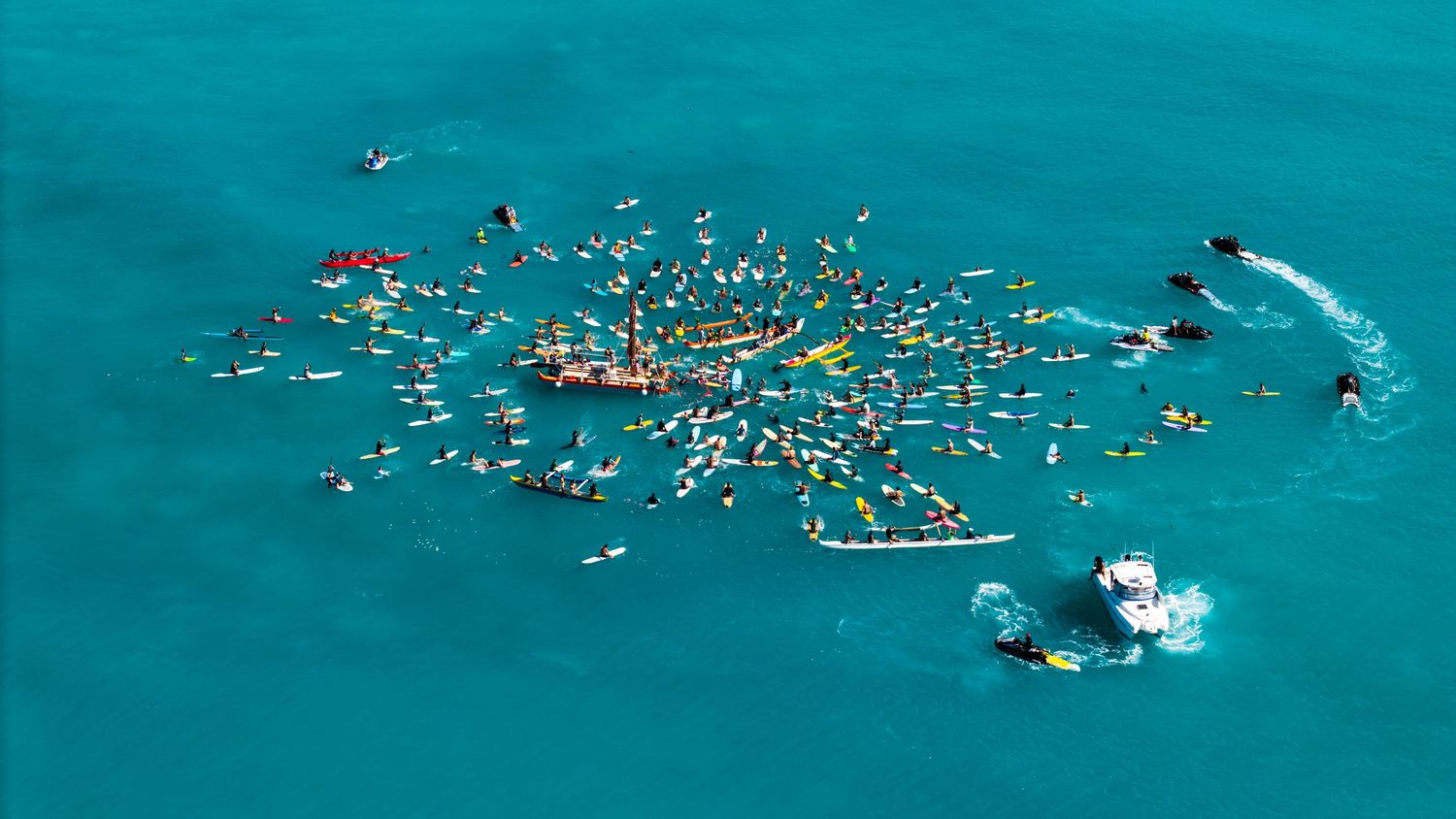 Aerial view of crystal clear ocean waters showing swimmers and reef patterns below.