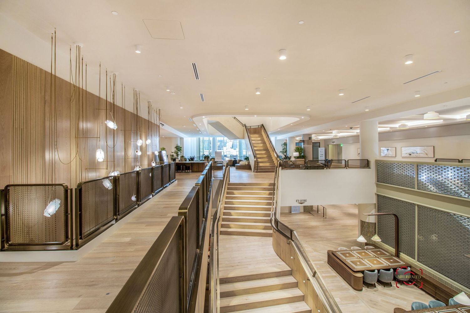 Contemporary office space with wooden staircase and glass railings in an open floor plan.