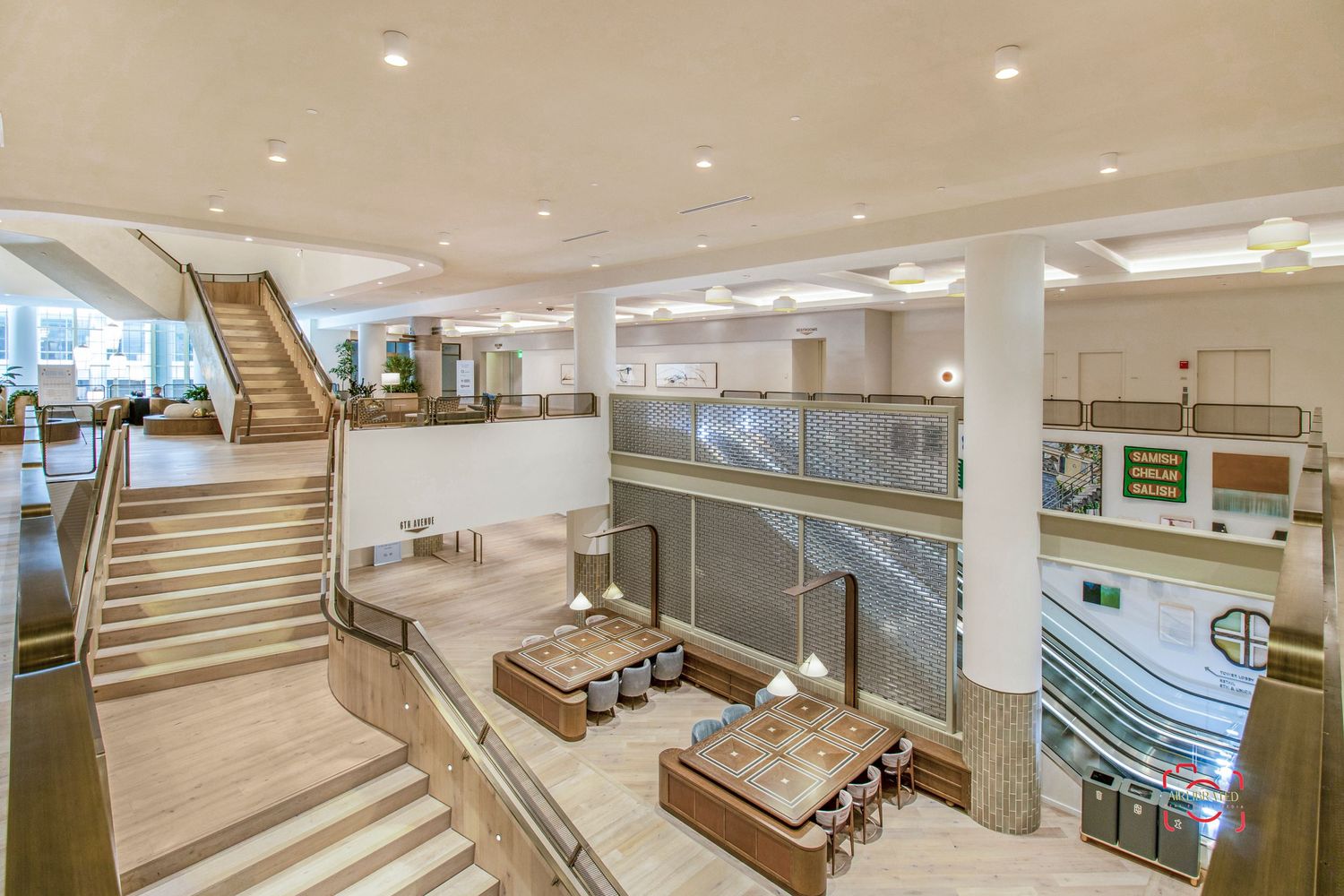 Multi-level office interior with wooden stairs, lounge seating, and modern lighting design.