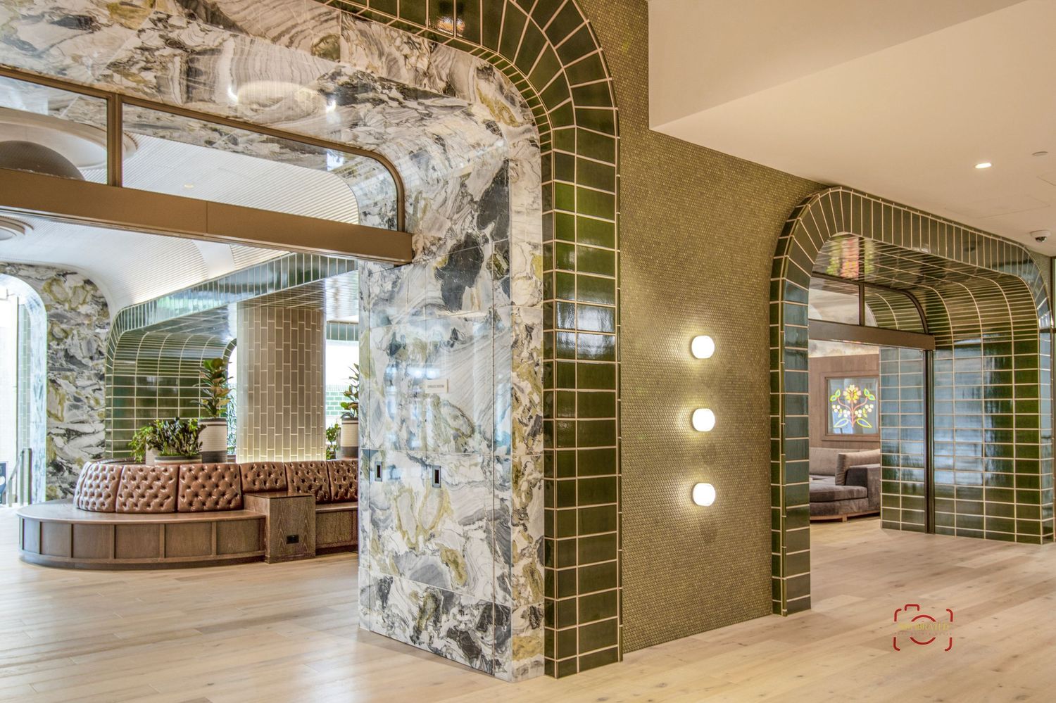 Luxury lobby interior with green tile archways, stone columns and brown leather seating.