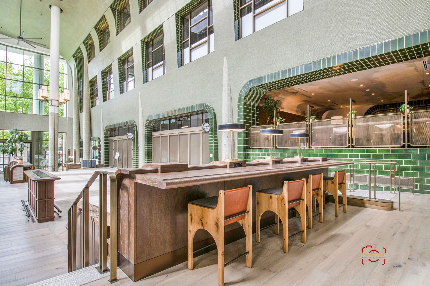 Modern bar area with wooden counters and green tile accents in an open-concept space.