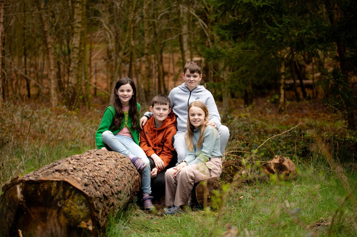Group seated on a large log in a wooded autumn setting.
