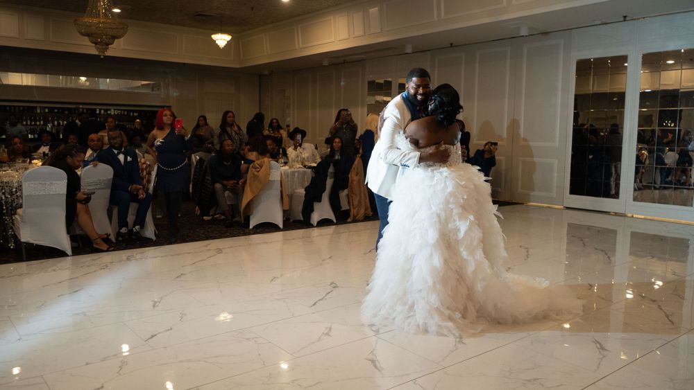 A couple sharing their first dance on a white dance floor at their wedding reception.