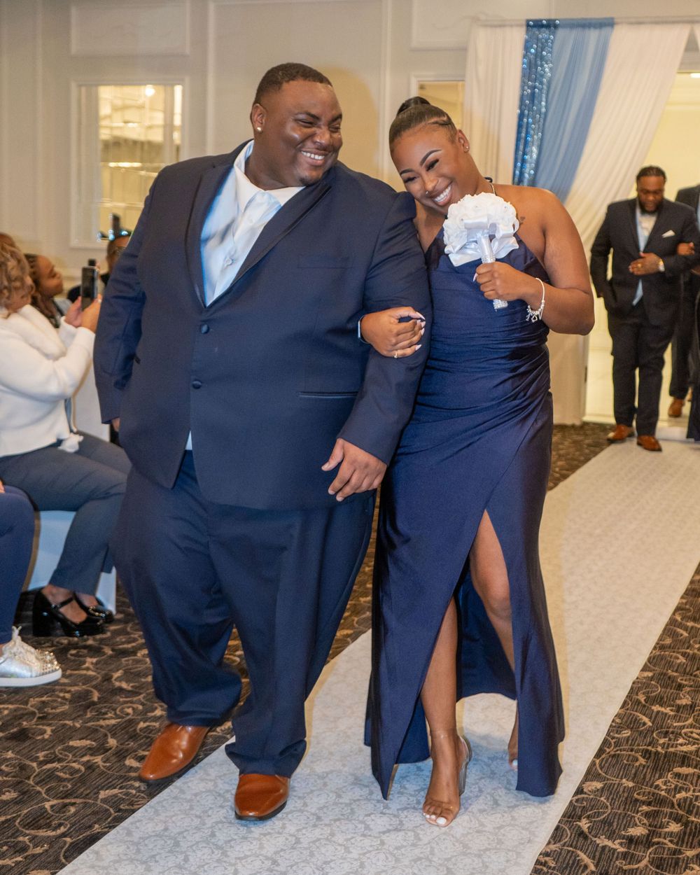 Wedding party member and guest sharing a laugh while walking down decorated aisle.