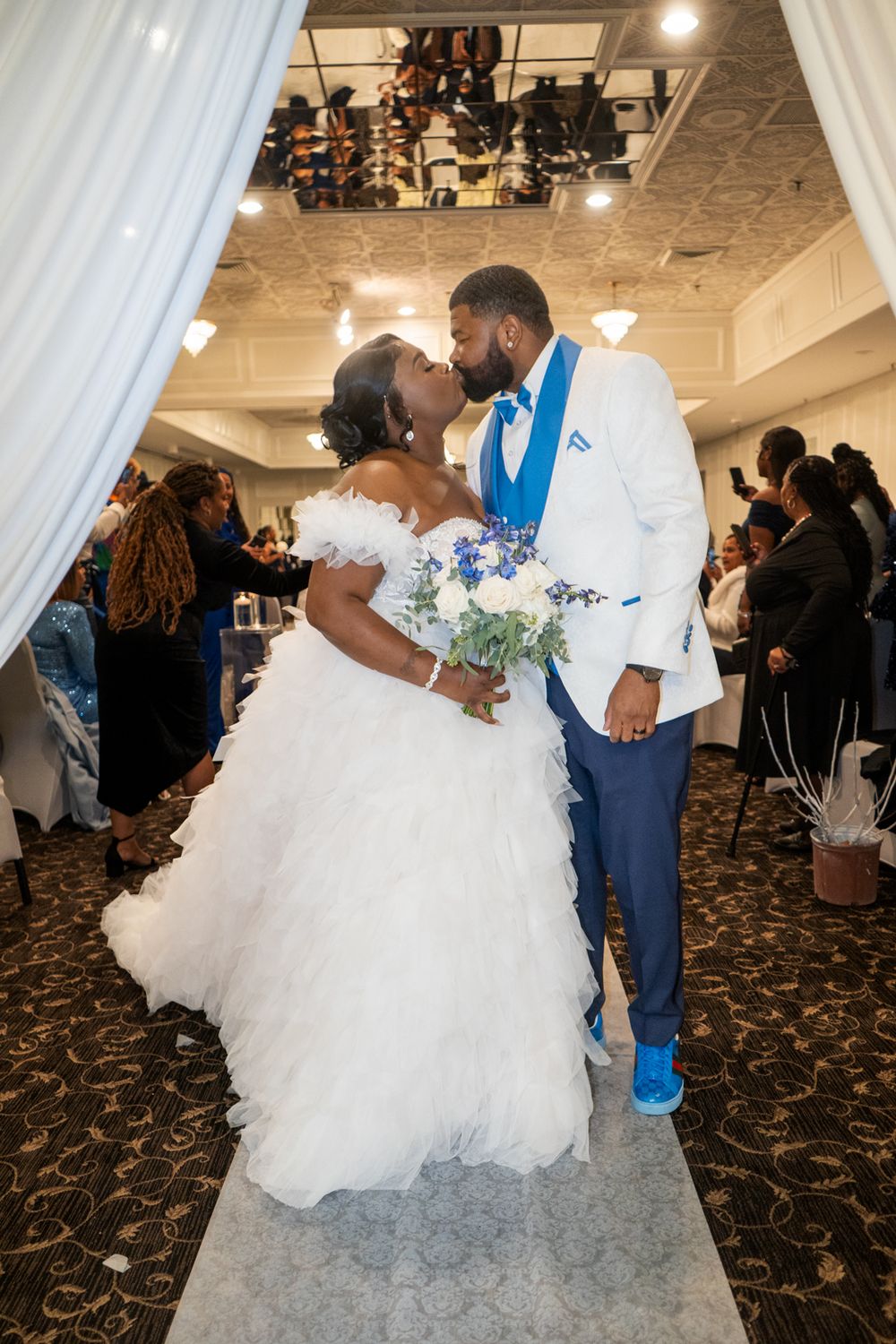 A couple shares a romantic moment under draped fabric at their wedding reception.
