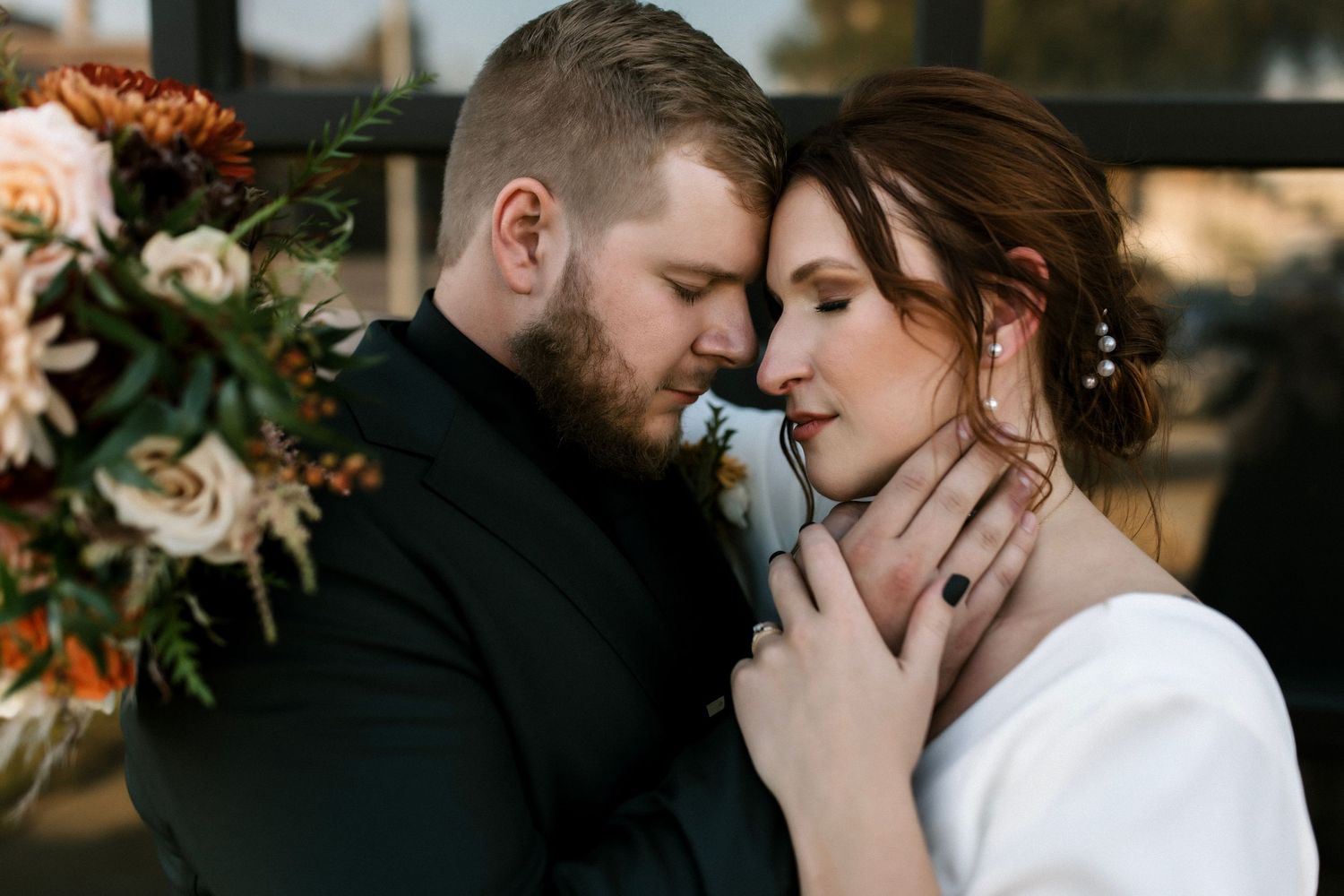 An intimate portrait of a couple in an emotional embrace with autumn floral arrangements.