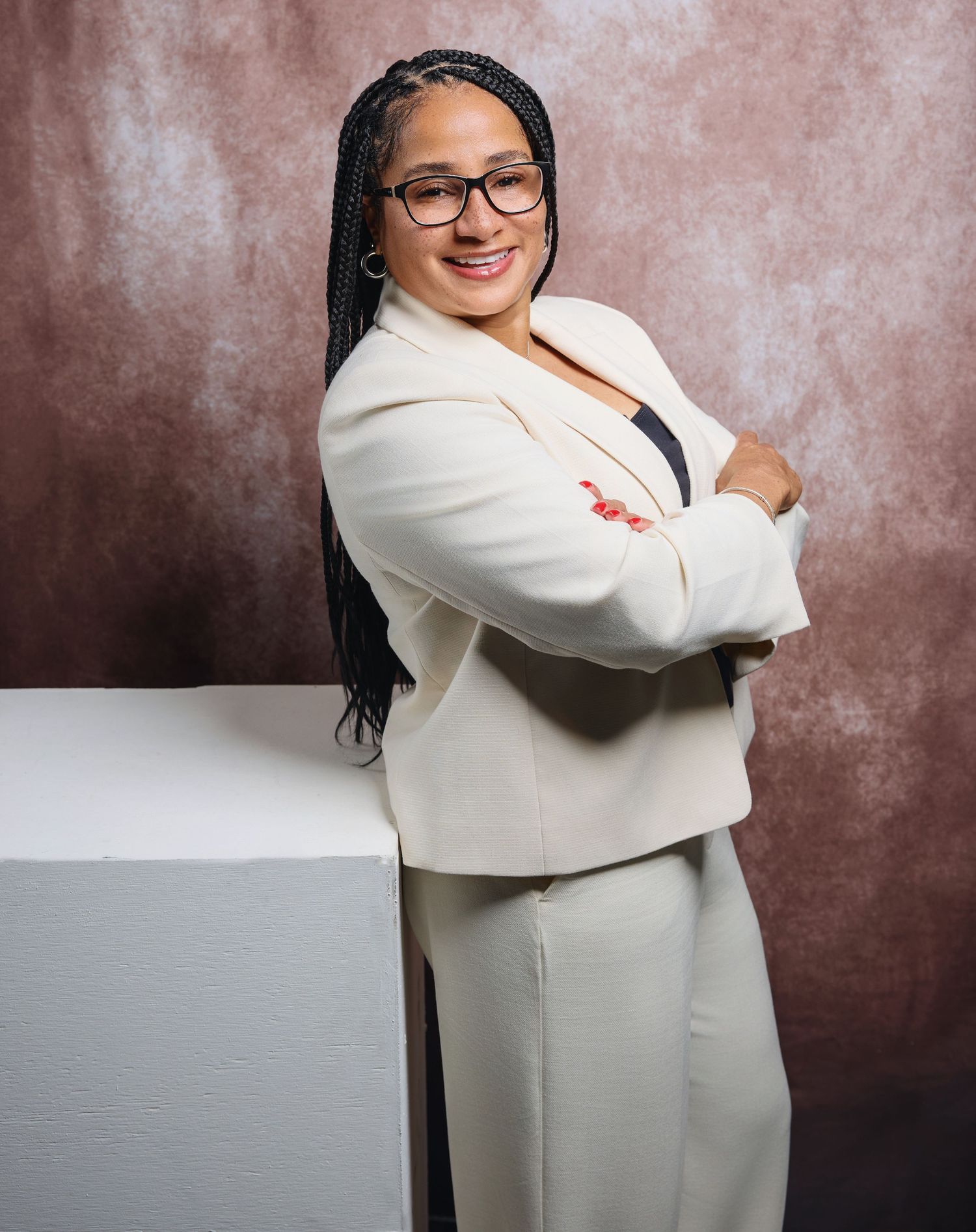 Professional studio portrait in white outfit against textured backdrop.