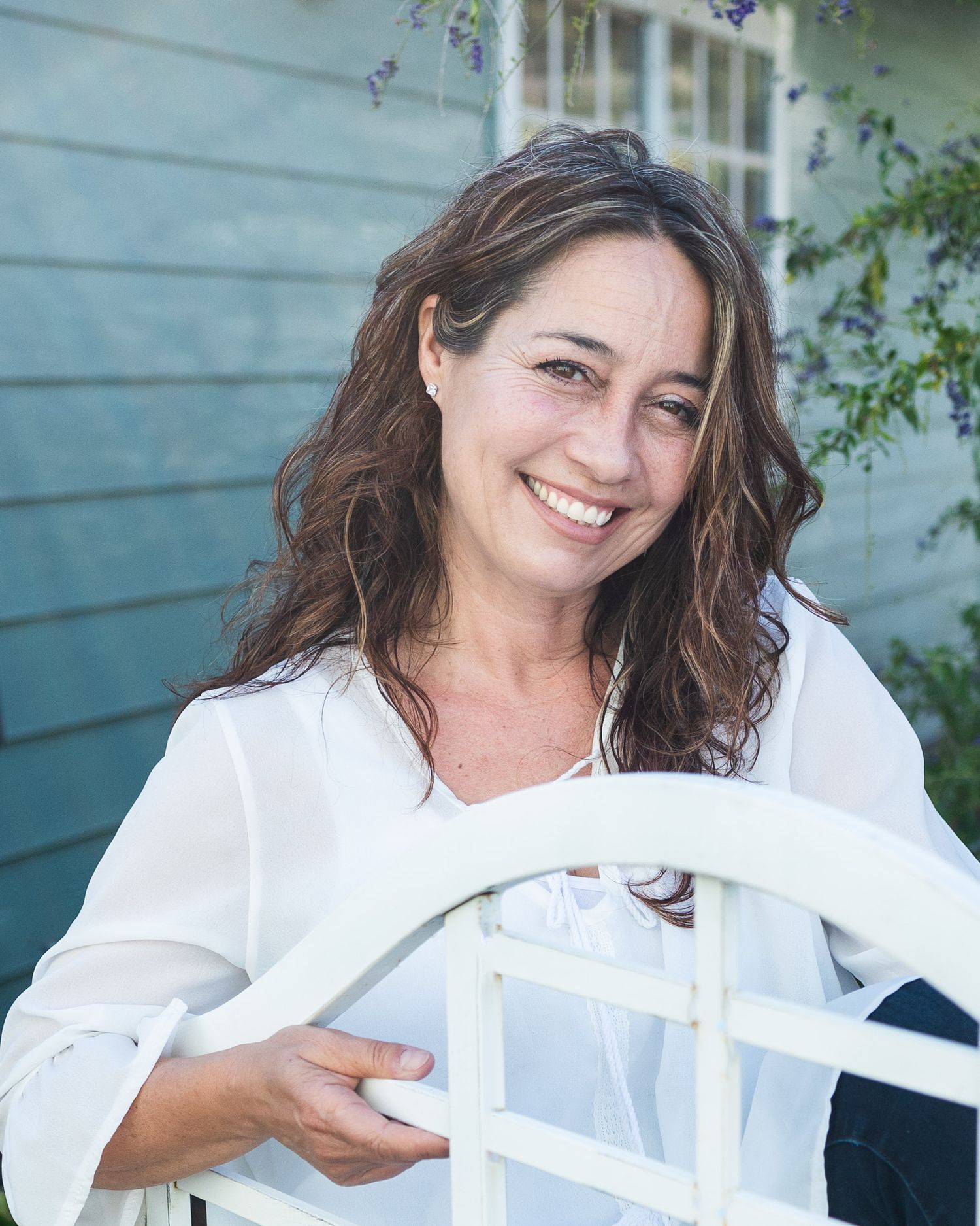 Woman in white sitting on porch chair with natural light.