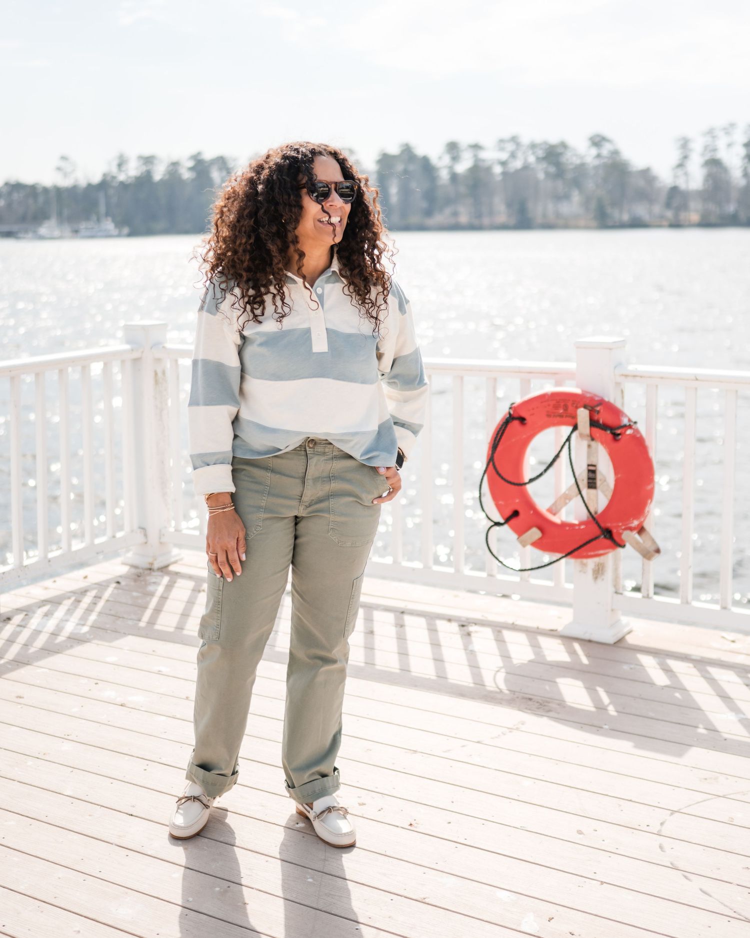 Casual lifestyle photo on a waterfront deck with striped sweater and life preserver.