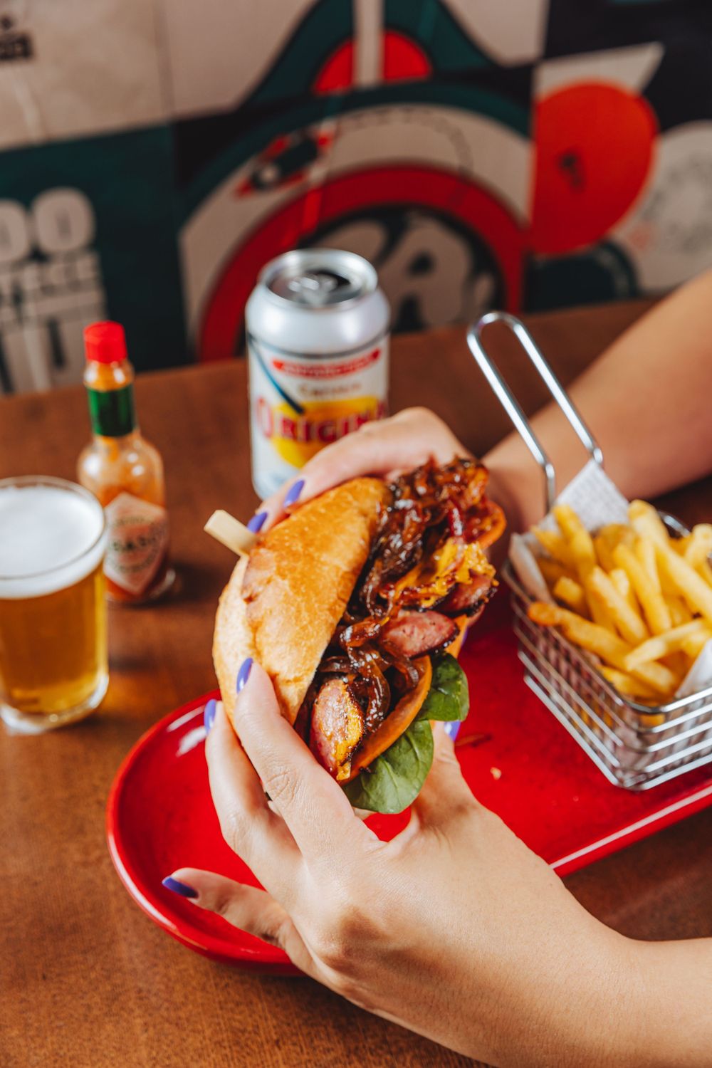 Juicy burger with bacon and lettuce served with golden french fries and beer in a casual dining setting.