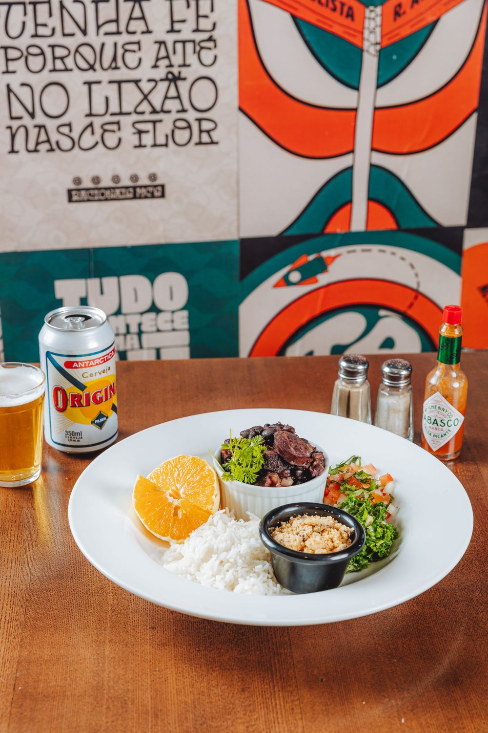 White plate with rice, orange slice, and small bowls of sides served with a can of Original beer.
