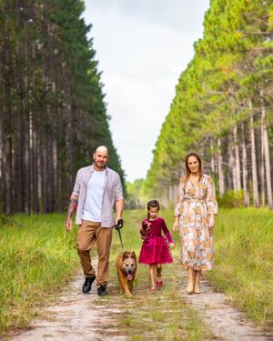 Mother father, daughter and their dog walking in the pine tree forest on the Sunshine Coast
