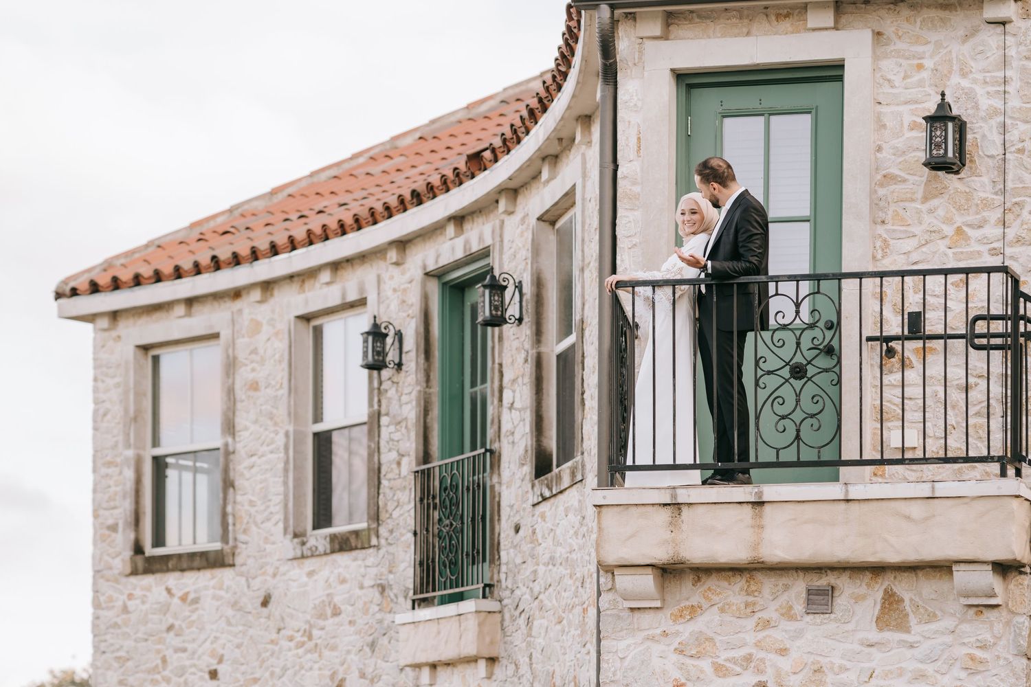 Couple standing on stone balcony of Mediterranean style building.