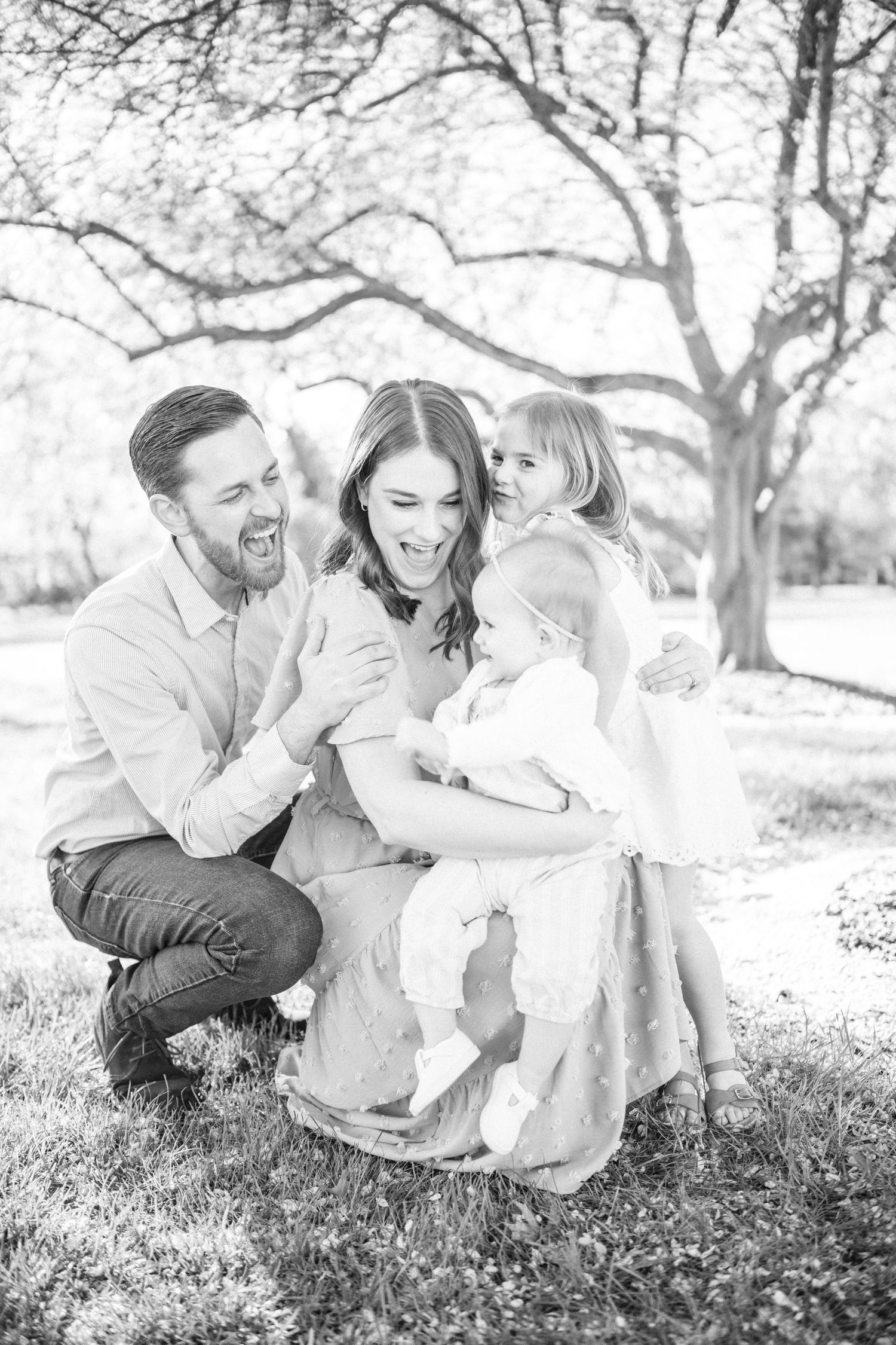 family photographer indianapolis, black and white image of family making big smiles at one another, parents kneeled down