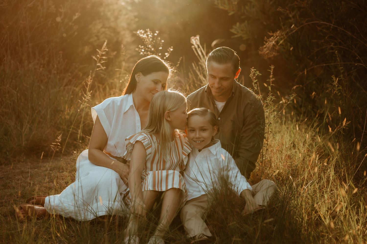 A dreamy beach scene with figures and a child in white dress playing by the water at sunset.