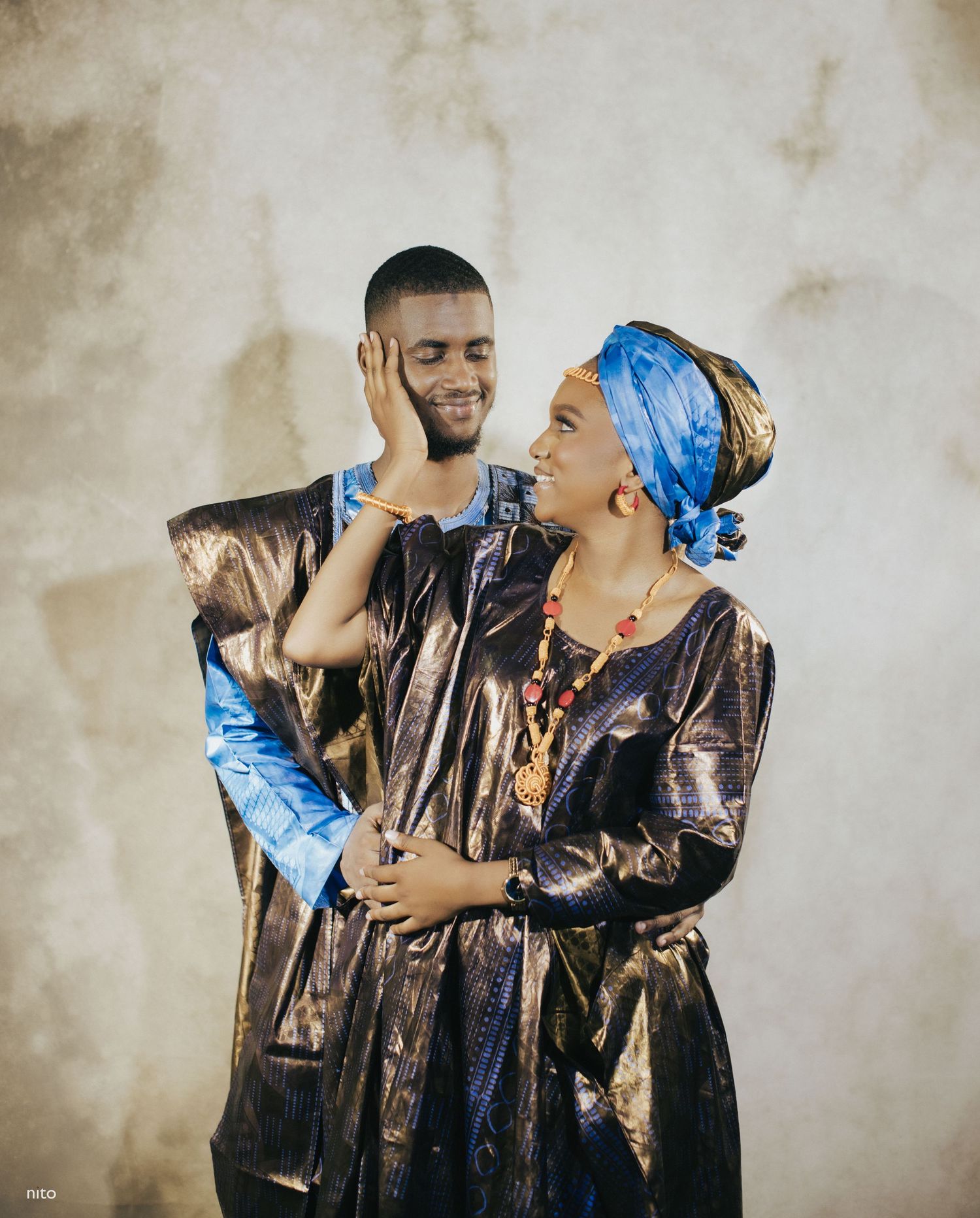 A couple in traditional African attire shares an intimate moment during a photo session.