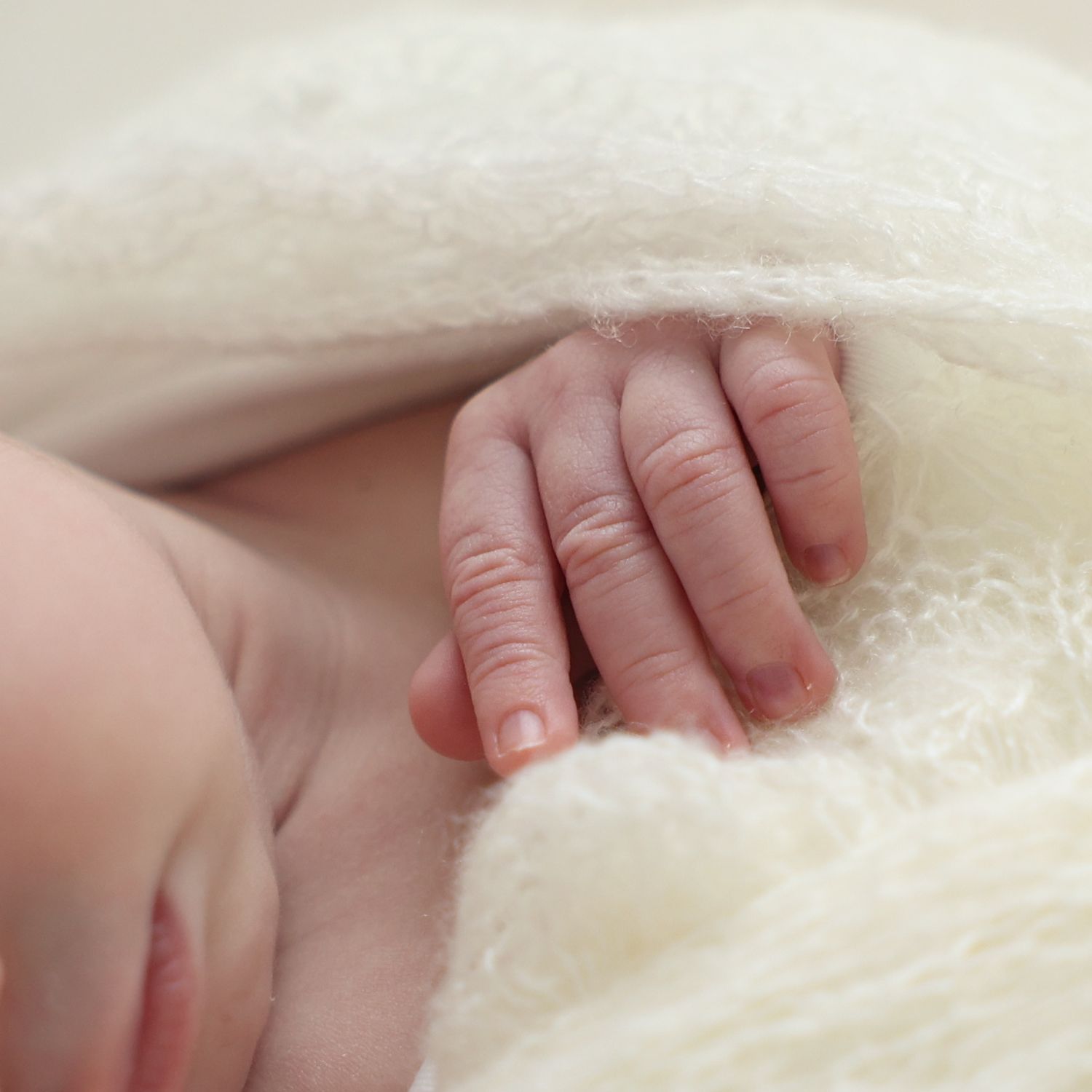 A close-up of a baby peacefully wrapped in a soft white blanket, showcasing their delicate features