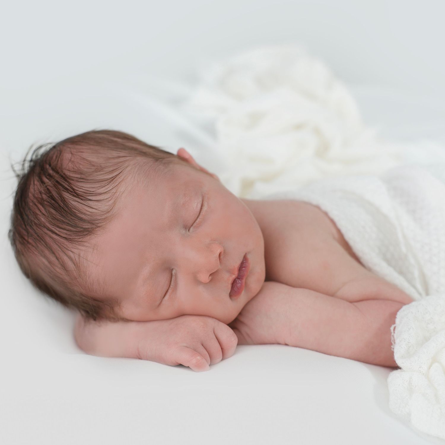 Newborn sleeping peacefully with his cheek resting on his hand