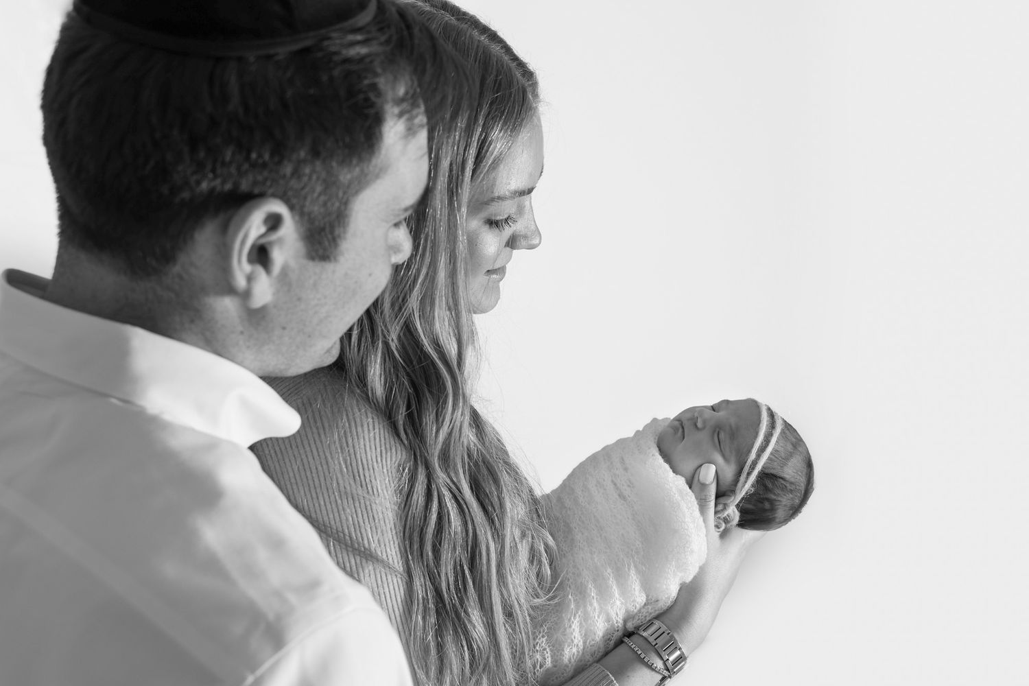 monochromatic close up image of mom and dad as the look on at their angelic newborn