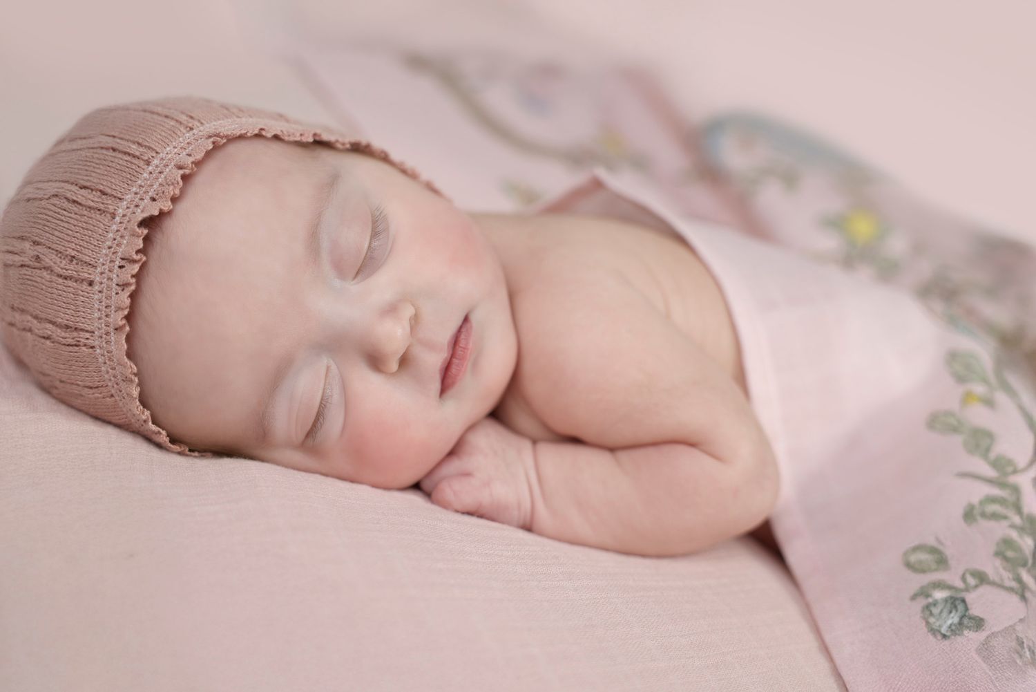angelic picture of sleeping newborn covered with a stylish patterned blanket