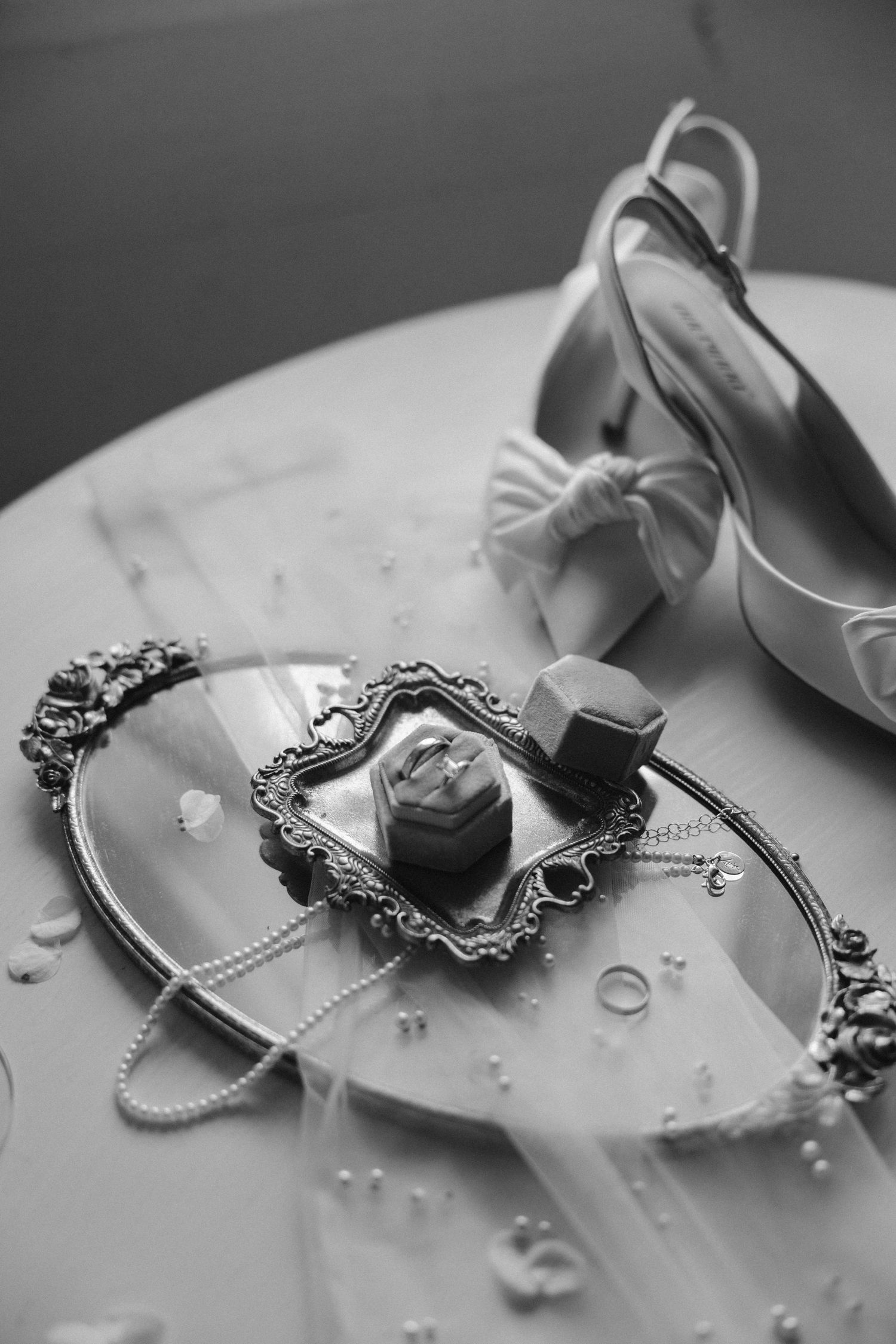 Elegant wedding accessories arranged on white with pearls, satin shoes, and vintage mirror capturing romantic details.