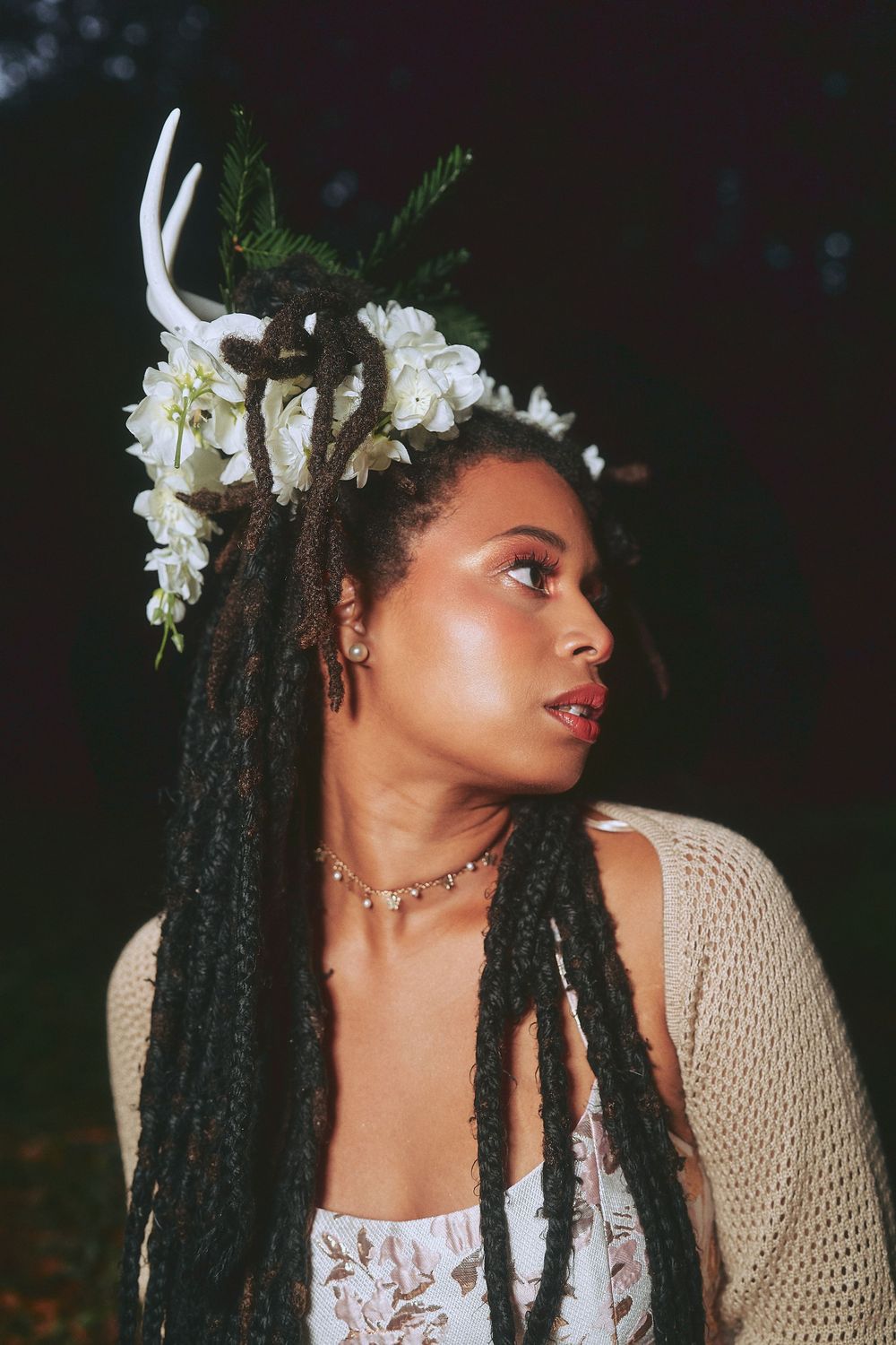 Woman with long dreadlocks wearing floral antler crown poses outdoors at night posing for a creative branding photoshoot in Fremont.