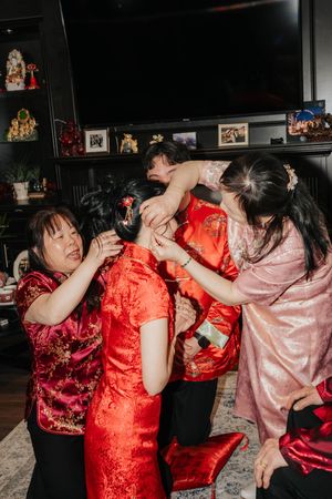 Group of friends in traditional red and pink Chinese qipao dresses dancing and celebrating together at a party.