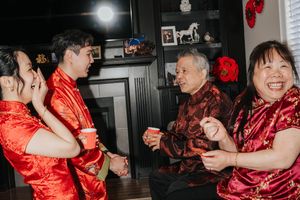 People in red traditional Chinese qipao dresses dance and celebrate at a festive indoor gathering.