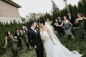 Wedding party celebrates on a beautiful green lawn during an outdoor reception ceremony.
