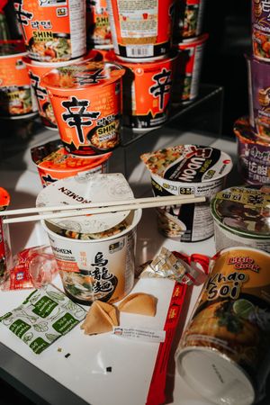 Empty instant noodle cups and packaging scattered on a table showing remnants of a quick meal.