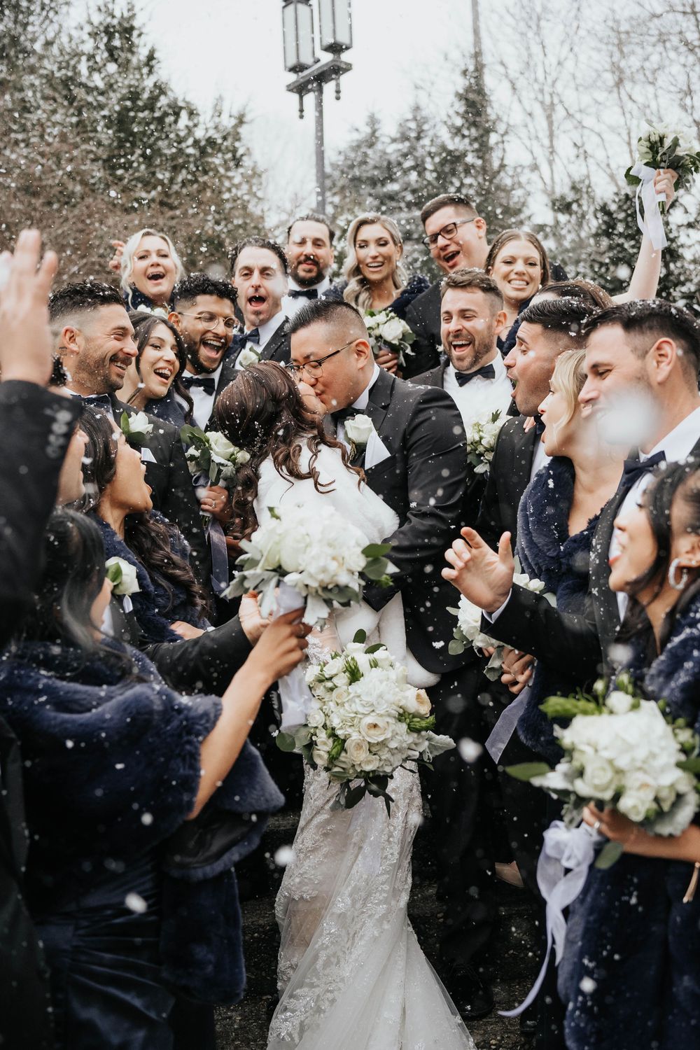 A joyful wedding celebration with guests throwing confetti outdoors during a winter celebration.