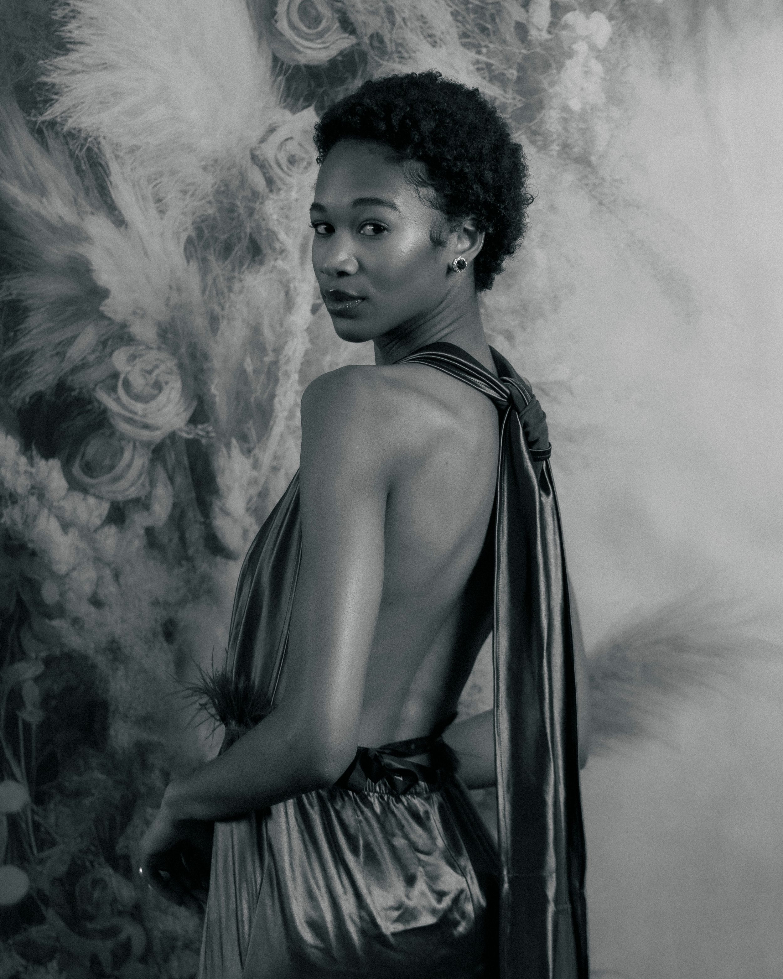 Dramatic fashion portrait with flowing fabric and moody lighting against textured background.