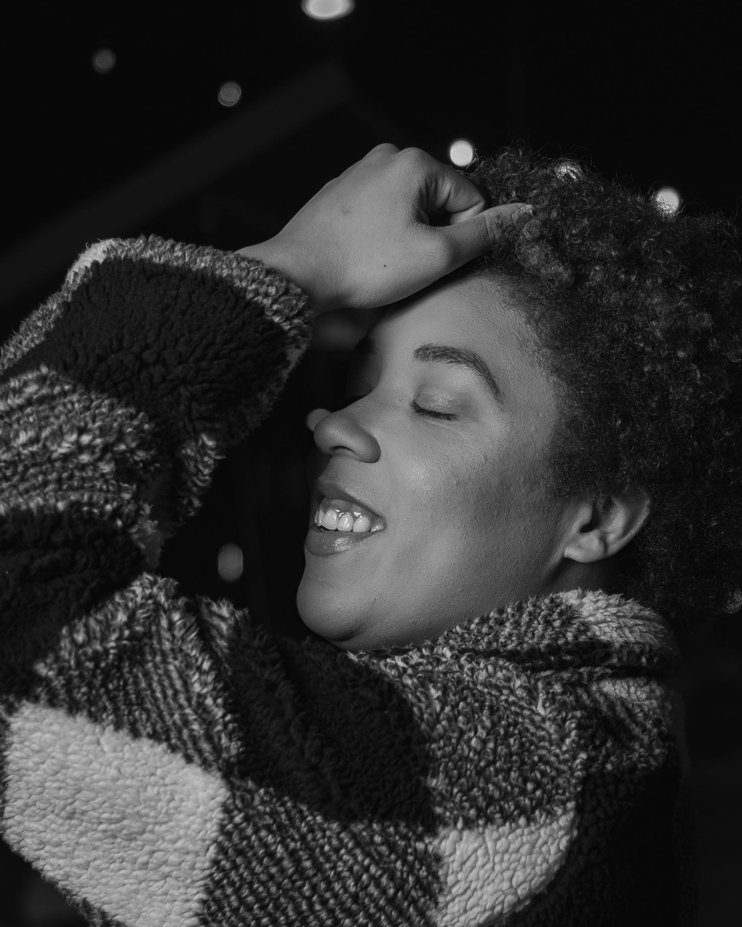 Black and white close-up portrait with cozy sweater and joyful expression.
