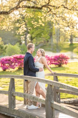 A couple sharing an intimate moment on a wooden bridge surrounded by spring blooms.