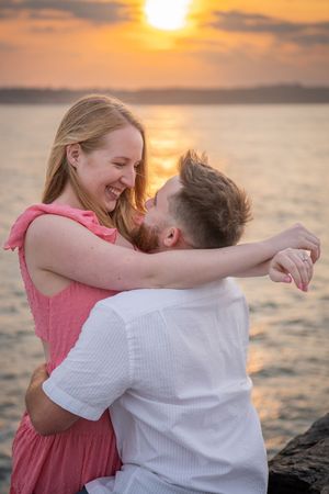 Romantic couple sharing intimate moment at sunset by the water's edge.
