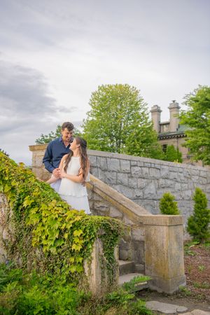 Couple sharing romantic moment on stone bridge surrounded by ivy and greenery.