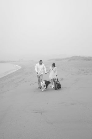 A couple walks along misty sand dunes in ethereal wedding photos.