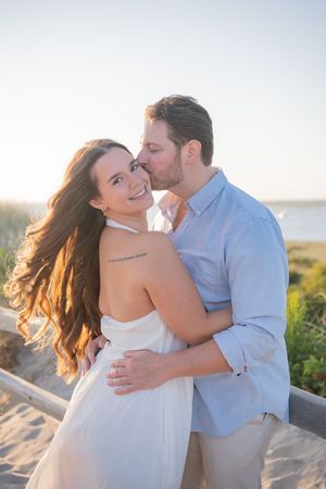 A couple embraces tenderly against a bright sky background during a romantic photoshoot.