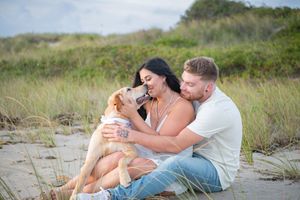 Romantic couple embraces on a sandy beach during a sunset photoshoot.