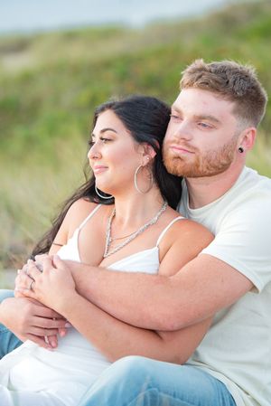 Intimate beach portraits showing tender moments between a couple in white attire.