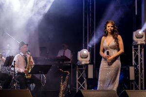 Singer - Ilish Retallick performing on stage at the 2025 ACC Christmas Carlos wearing a long silver Dress, photo by Jason Robins