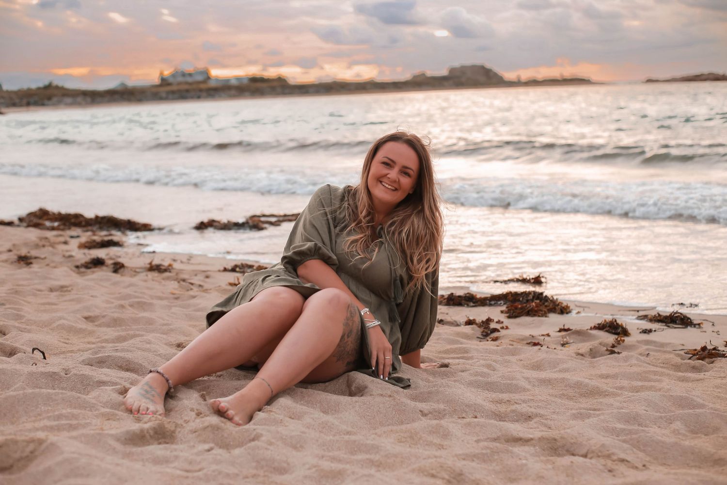 Person relaxing on sandy beach during golden sunset with waves crashing in the background.