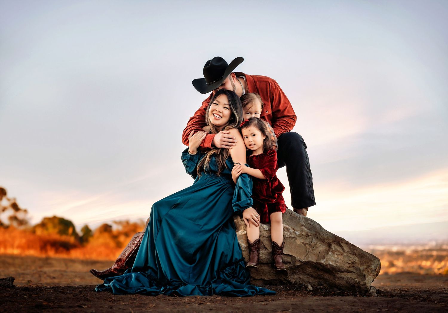 Family with dog enjoying sunset together in field.