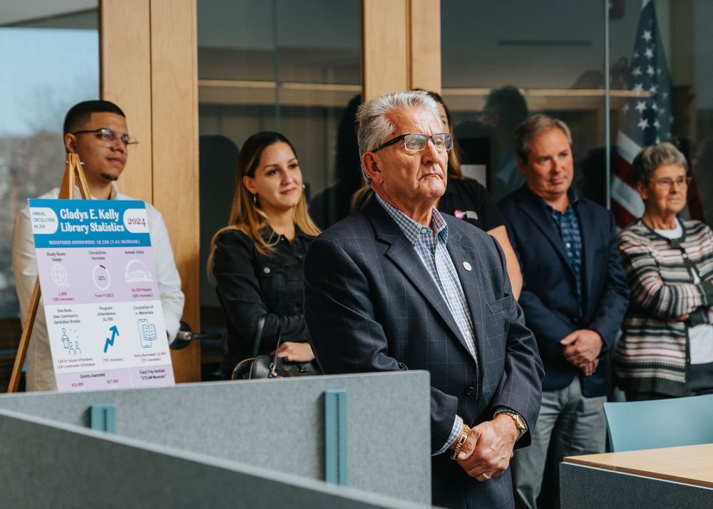 A group of diverse professionals stand attentively at a podium during a presentation or press conference.