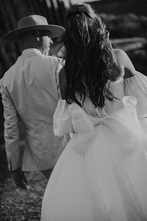 Black and white wedding photo series showing a couple walking together with the bride wearing a flowing white dress.