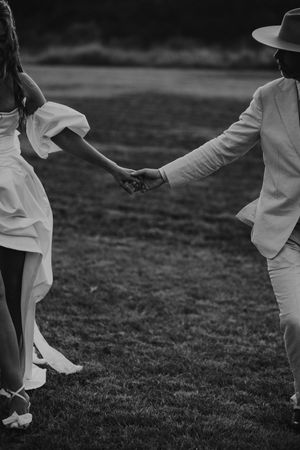 Black and white image of people in white outfits dancing together on a grassy lawn outdoors.
