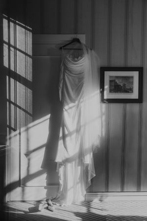 Dramatic black and white photograph of sunlight casting window shadows on interior walls with hanging white fabric.